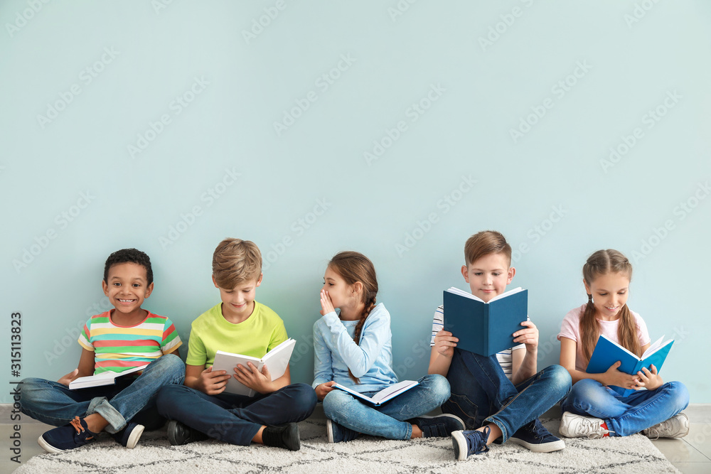 Cute little children reading books on color background