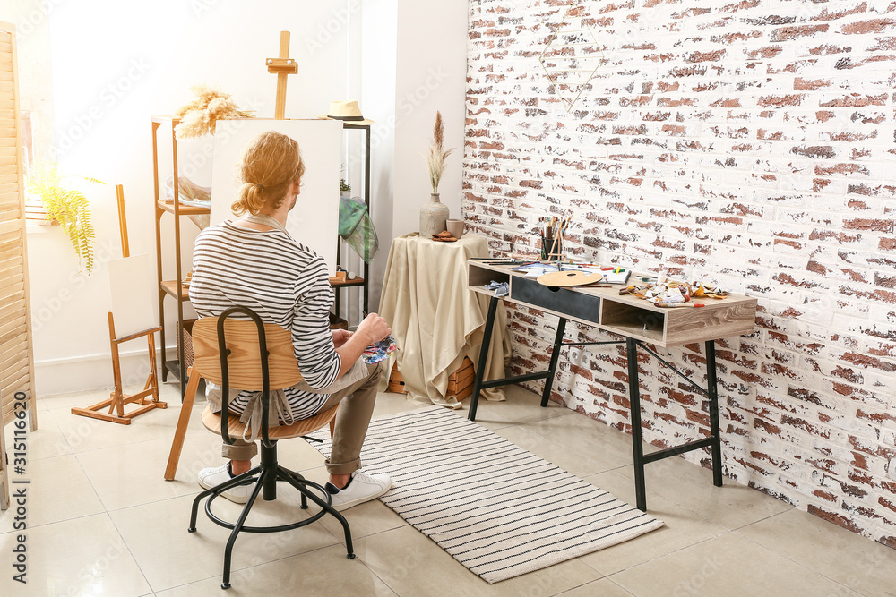 Young male artist painting at home