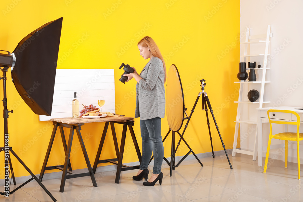 Young woman taking picture of cheese and wine in professional studio