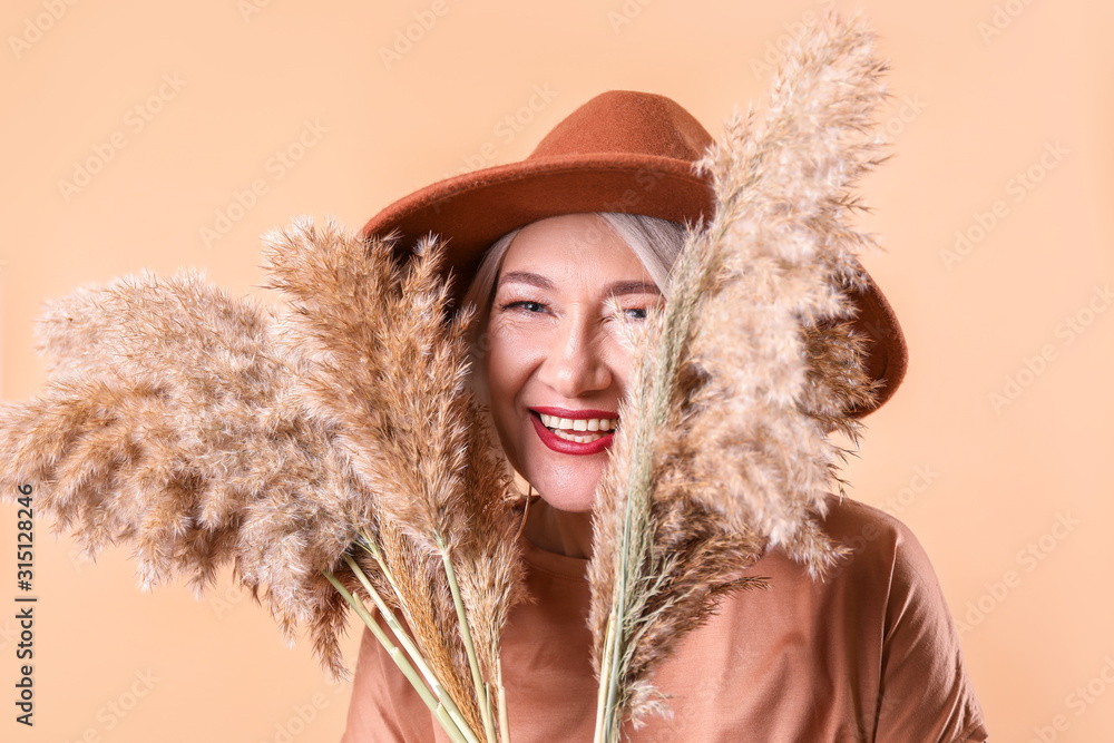 Fashionable mature woman on color background