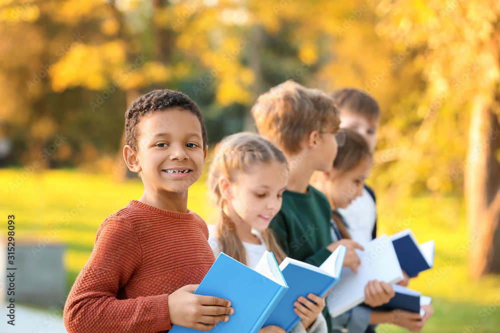 Cute little children reading books outdoors