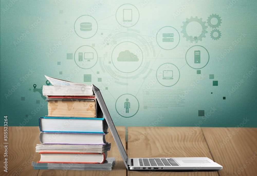 Stack of books with laptop on wooden table