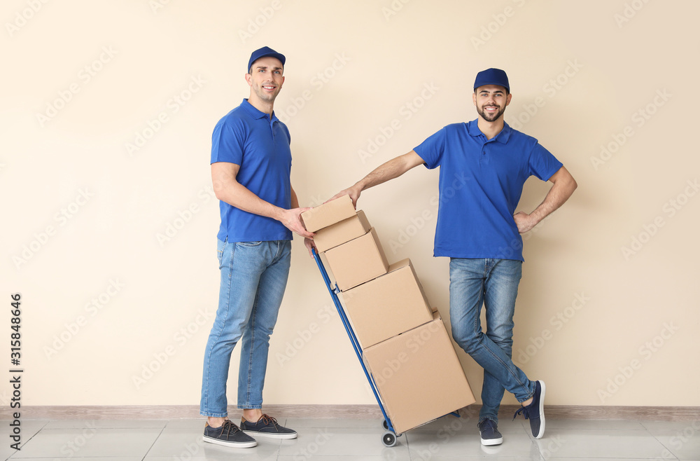 Delivery men with boxes near color wall