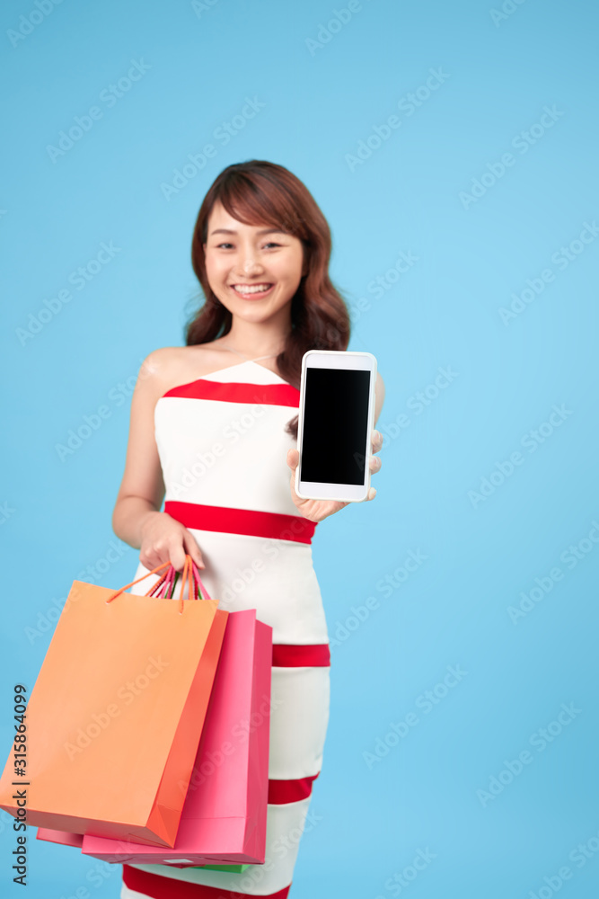 Stylish young woman with shopping bags and smart phone in hands