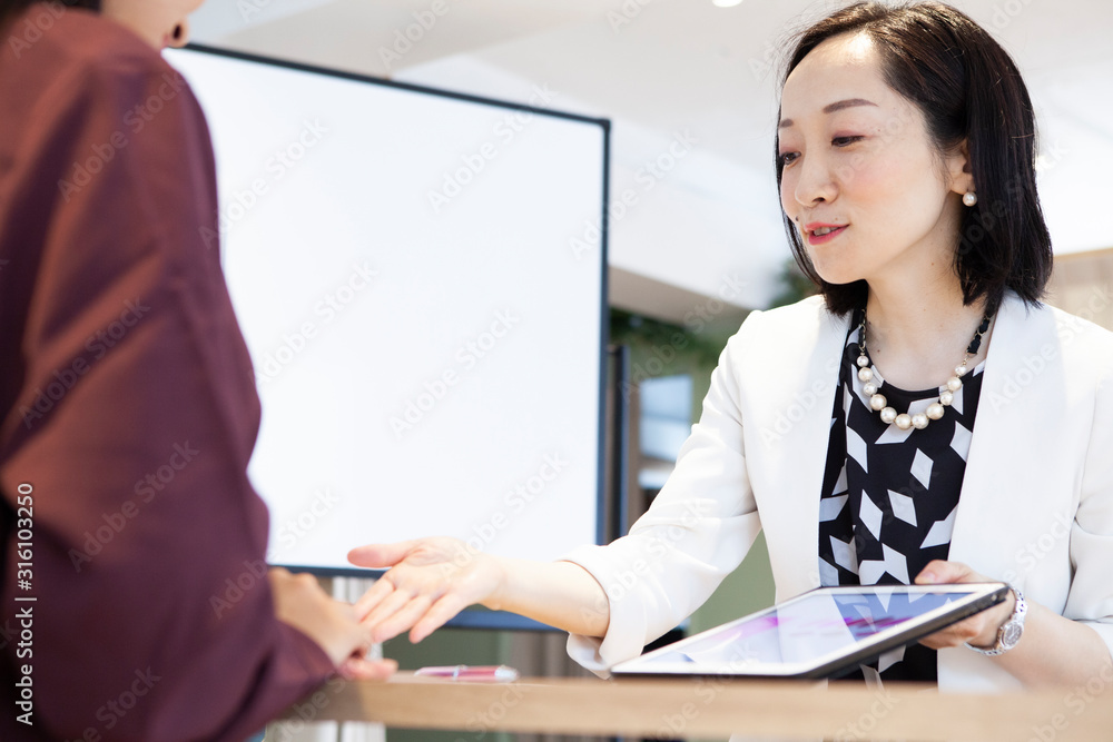 女性社員たちがタブレットを見ながら打ち合わせをしている