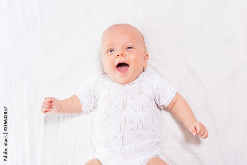 Laughing happy little infant baby boy with open mouth and shining eyes view from above