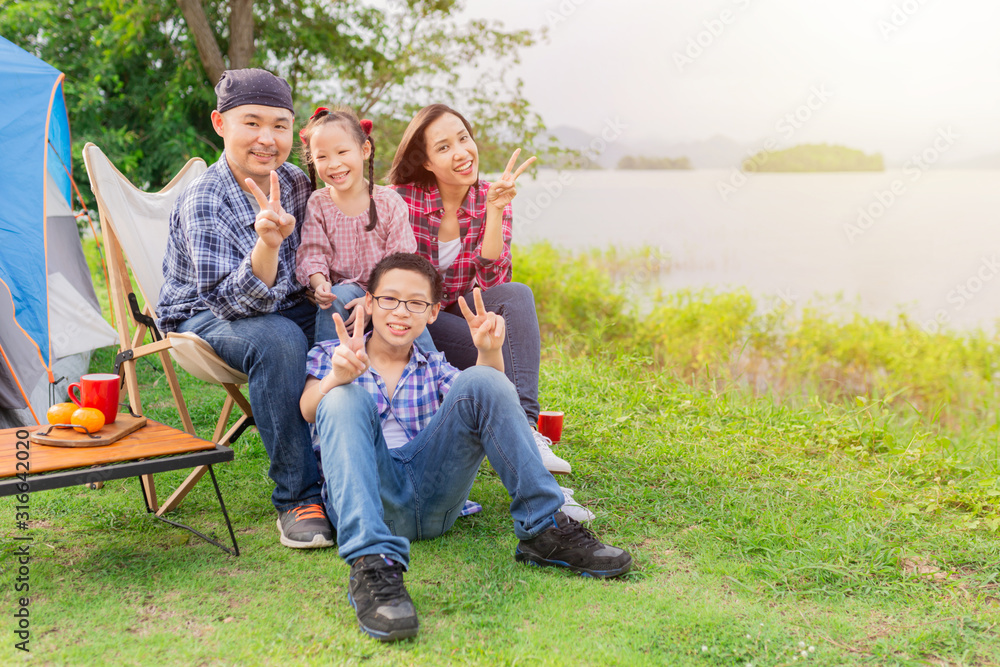 亚洲家庭在森林里旅行和露营，他们坐在湖边，心情愉快。