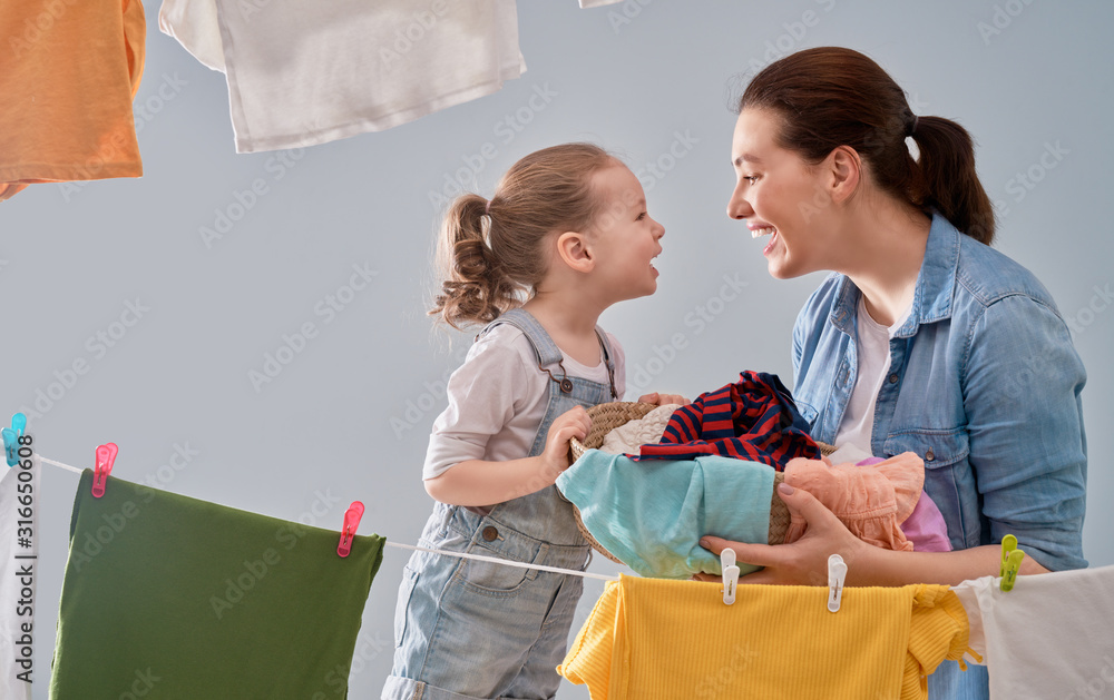 woman and girl hanging clothes on a rope