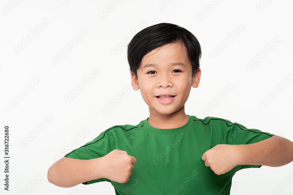 Portrait of cute smart young Asian boy shows winning gesture and smiling at camera, celebrating succ