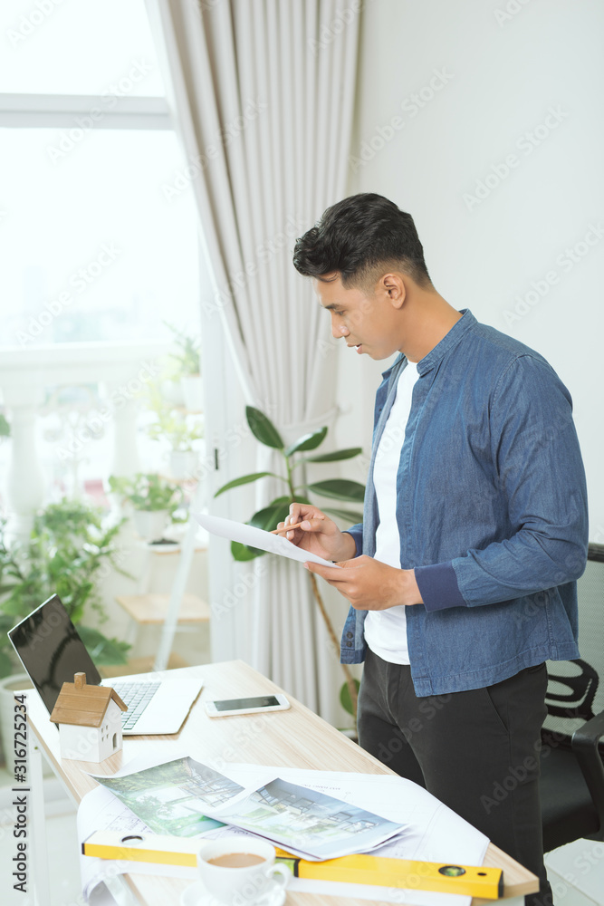 Young engineer. Successful busy man drawing something while working in the office