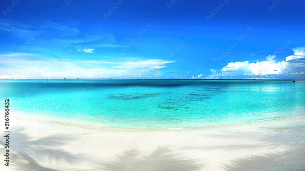 Beautiful beach with white sand, shadows from leaves of palm trees, turquoise ocean water and blue s