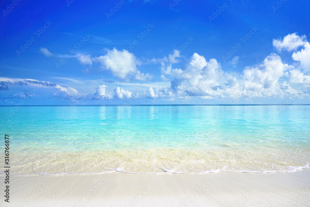 Beautiful sandy beach with white sand and rolling calm wave of turquoise ocean on Sunny day. White c