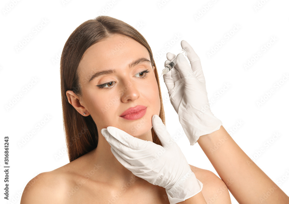 Young woman receiving filler injection against white background