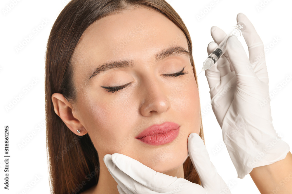 Young woman receiving filler injection against white background