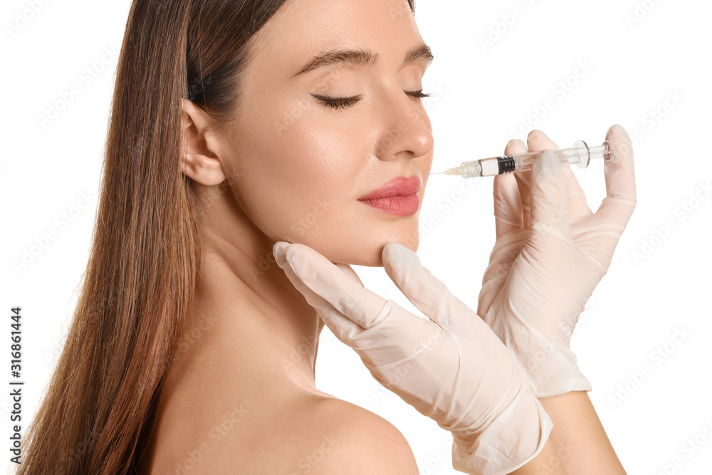 Young woman receiving filler injection against white background