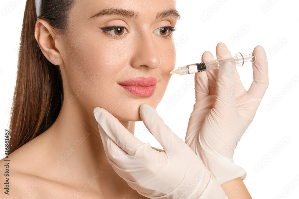 Young woman receiving filler injection against white background