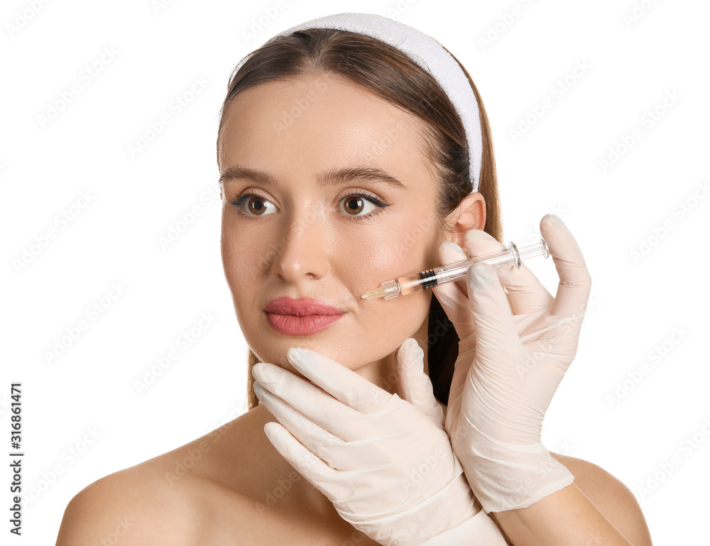 Young woman receiving filler injection against white background