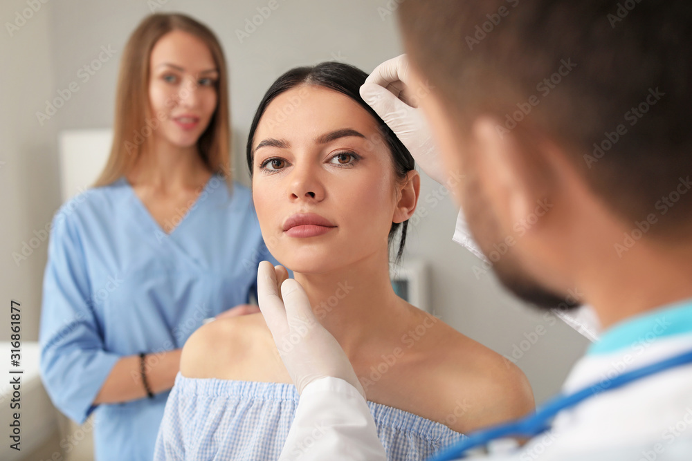 Plastic surgeon examining young womans face prior to operation in clinic