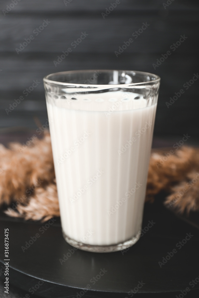 Glass of tasty milk on dark table