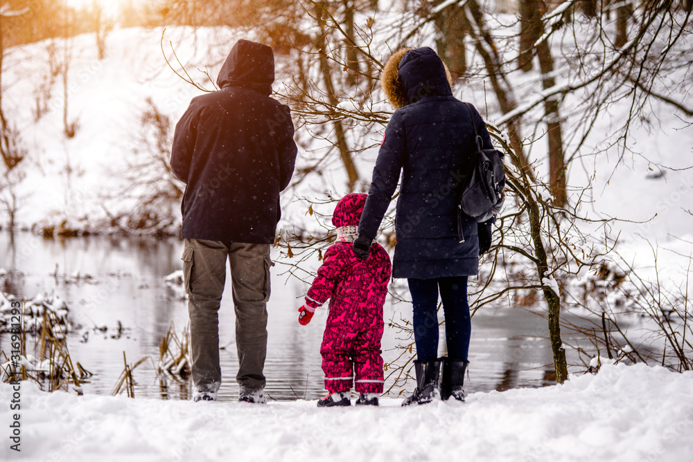 A couple with his son stands on the river Bank in winter