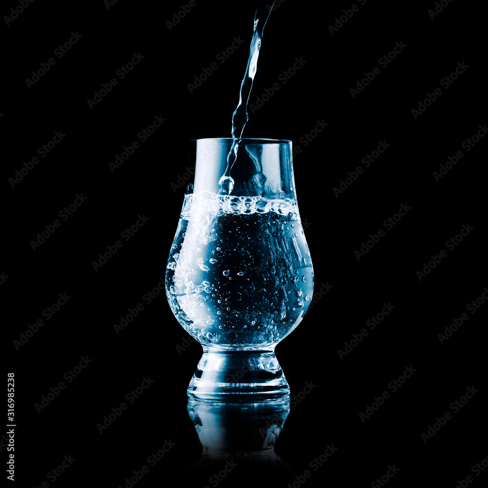 Liquid poured into a glas - blue toned isolated on black