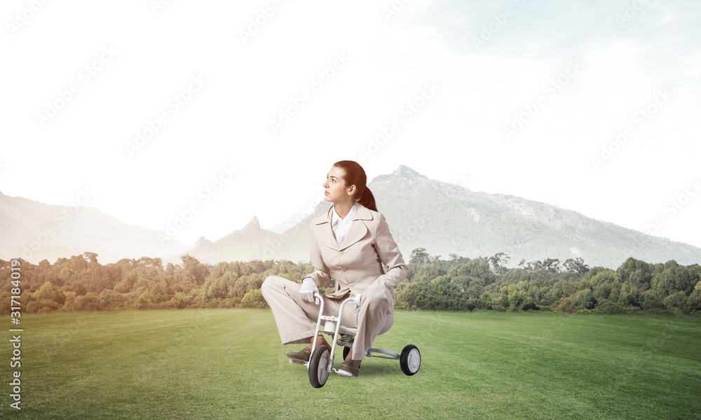 Beautiful young woman riding childrens bicycle