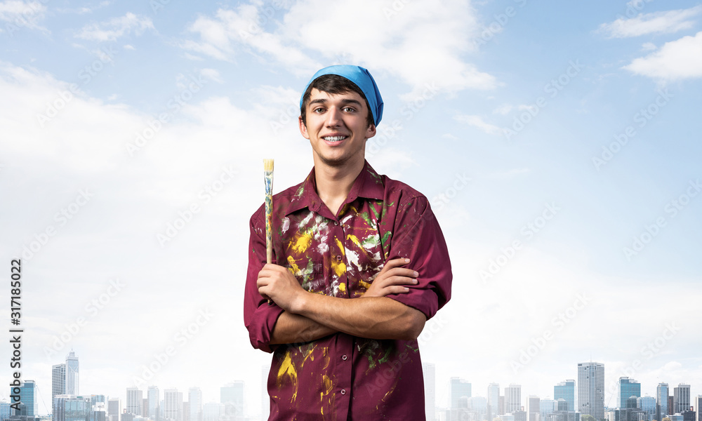 Smiling young painter artist holding paintbrush