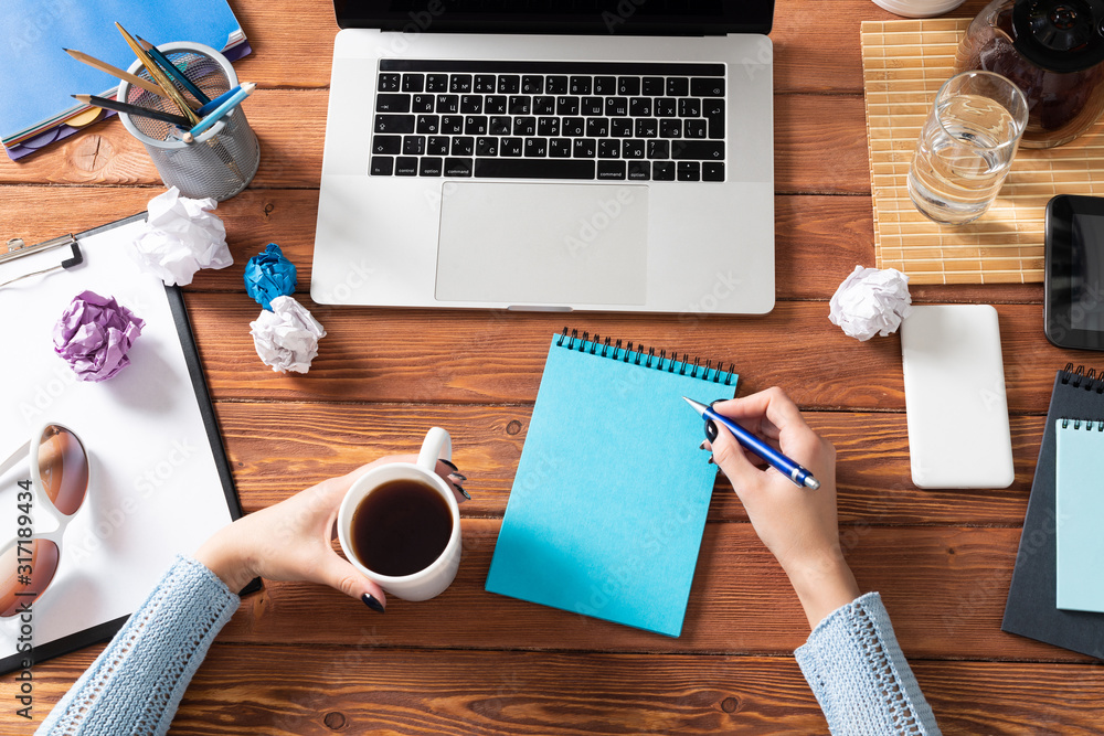 Woman writing in notebook with pen at desk