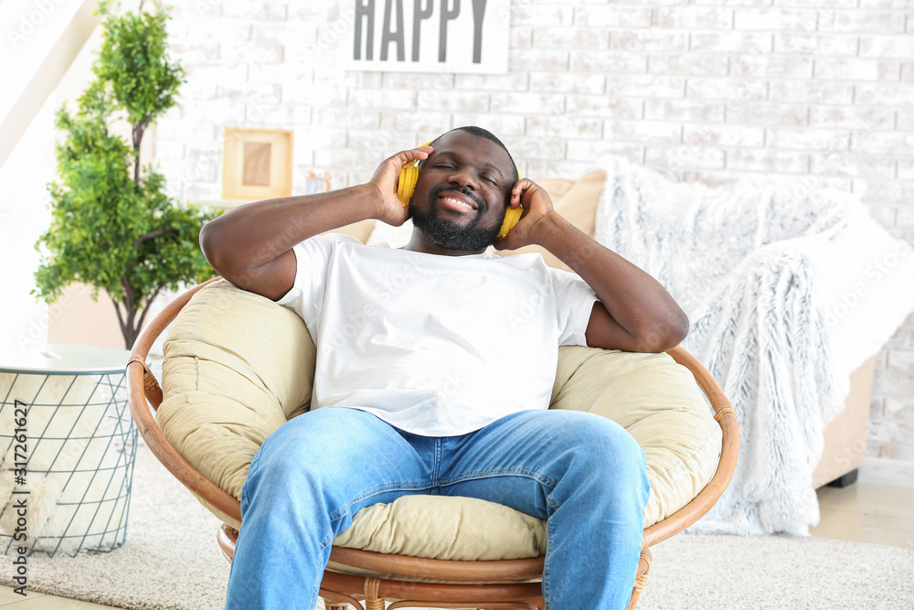 African-American man listening to music while sitting in armchair at home