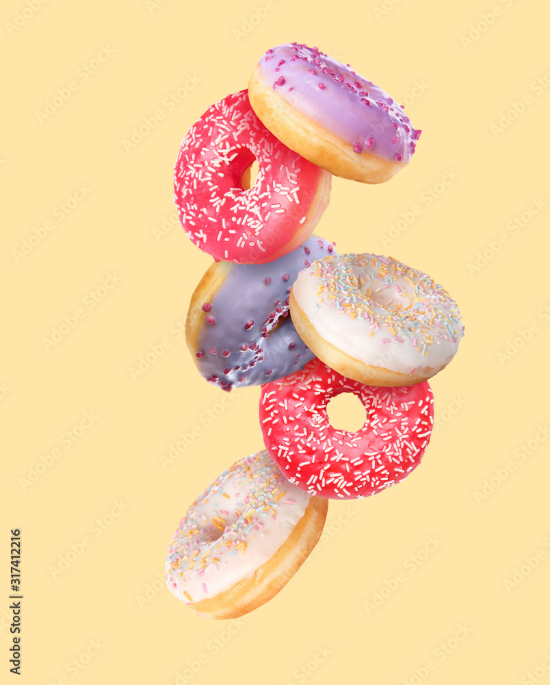 Sweet flying donuts on color background