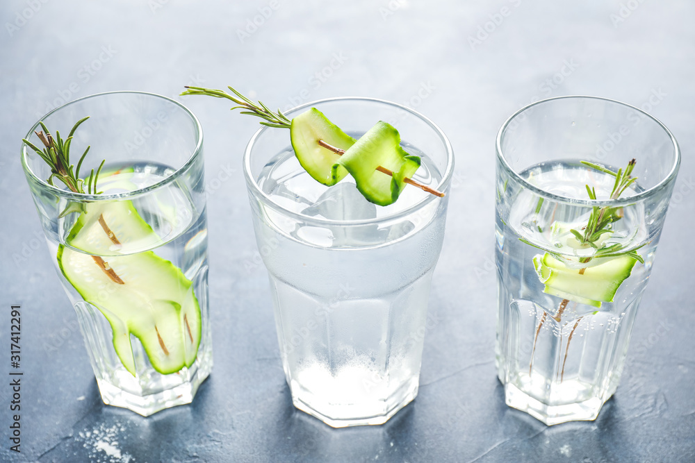 Glasses of cold cucumber water on dark background