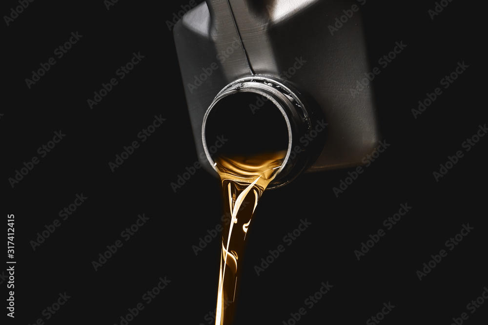 Can with pouring car oil on dark background