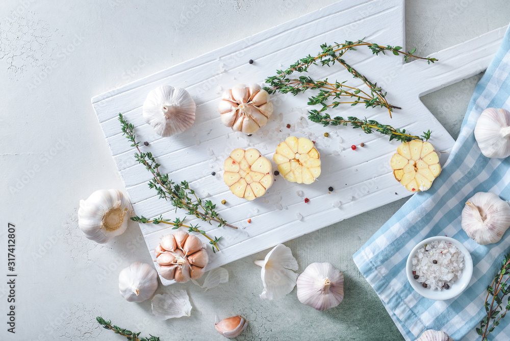 Fresh garlic with spices and herbs on light background