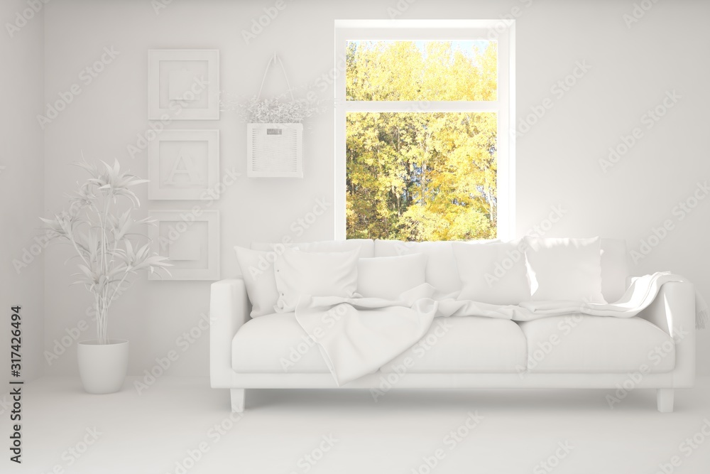 Stylish room in white color with sofa and autumn landscape in window. Scandinavian interior design. 