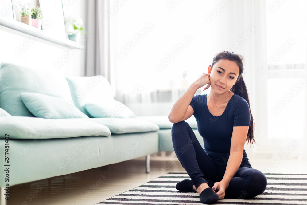 年轻的亚洲女孩在家训练后在客厅休息