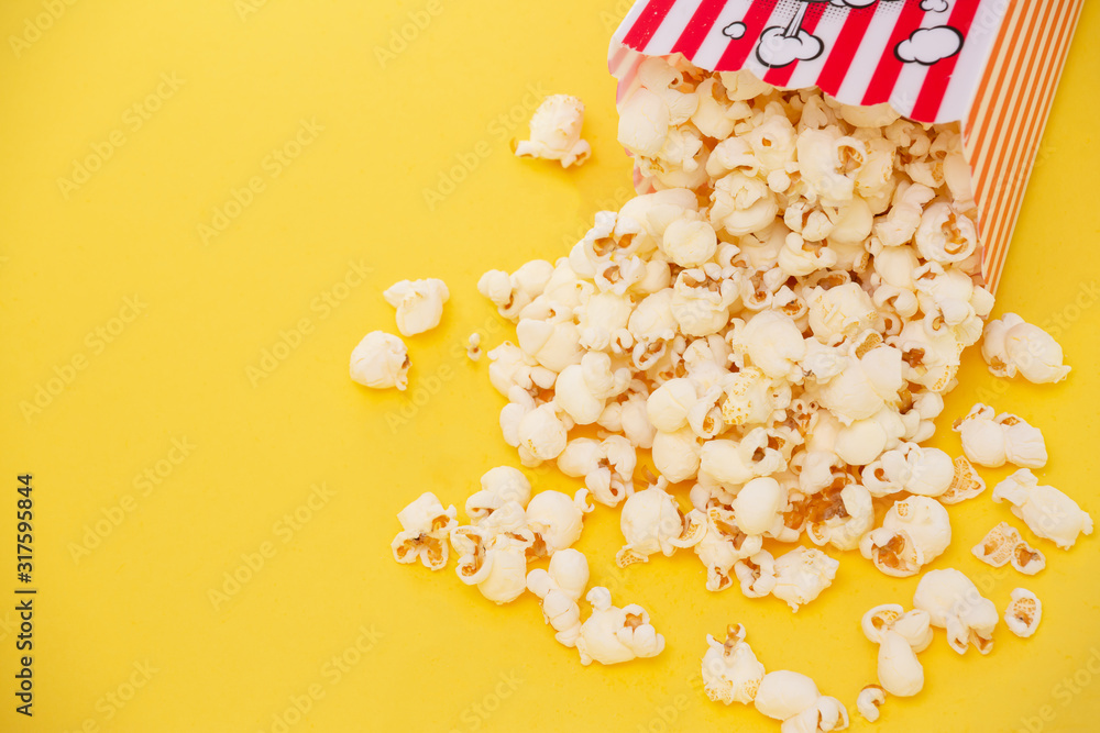 Butter popcorn in a red popcorn cup, snack in the house or cinema on a yellow background