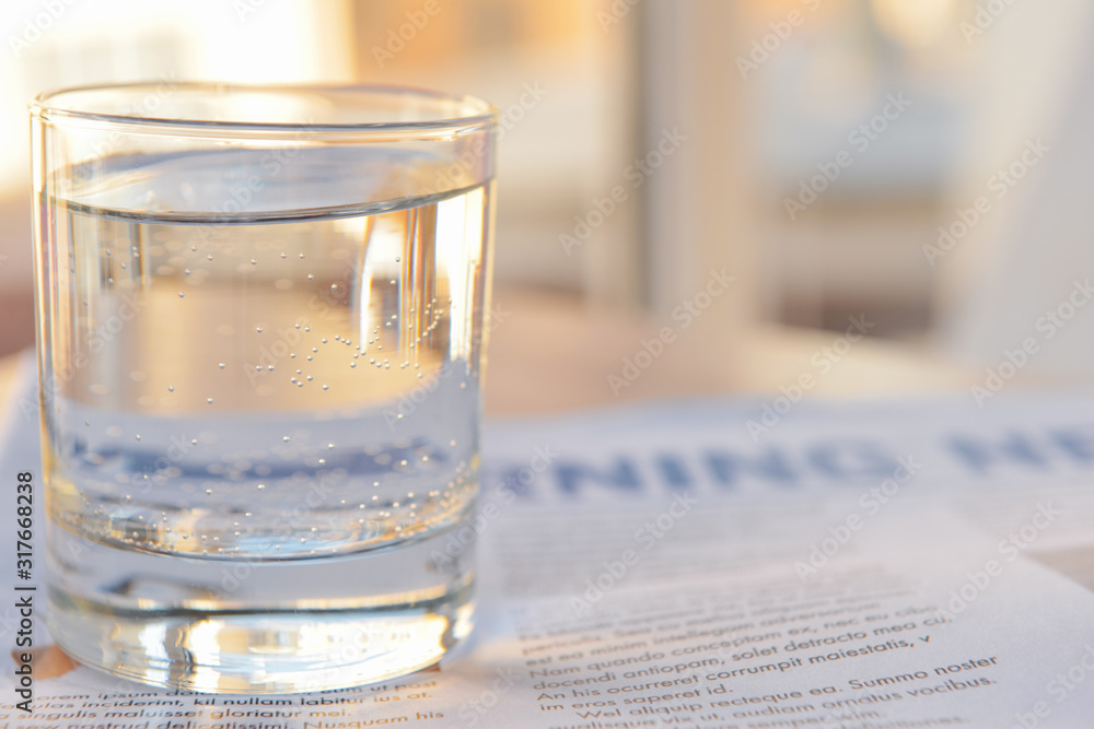 Glass of clean water and newspaper on table