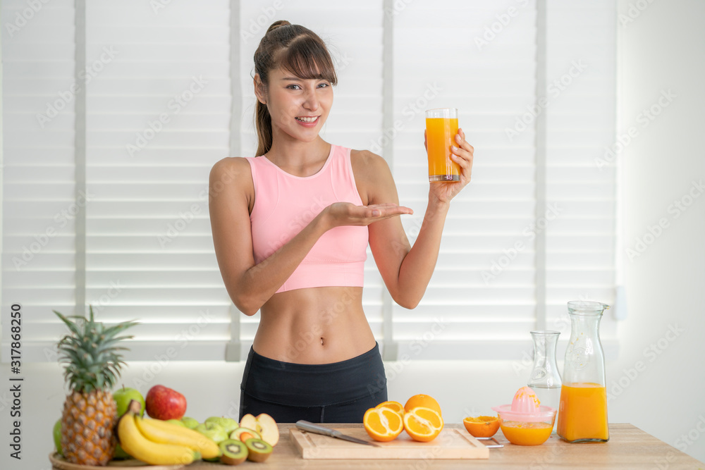 Asian girl make an orange juice by hand at home after finished exercise