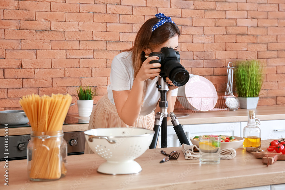 Young photographer taking picture of pasta in kitchen