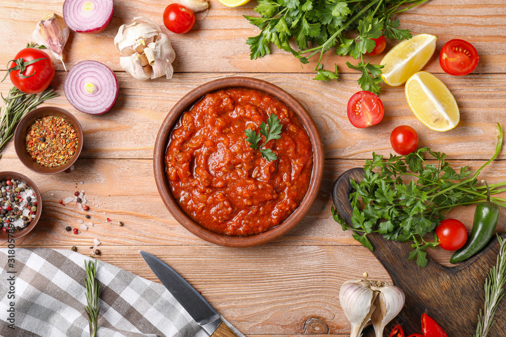 Plate with tasty sauce and ingredients on wooden background