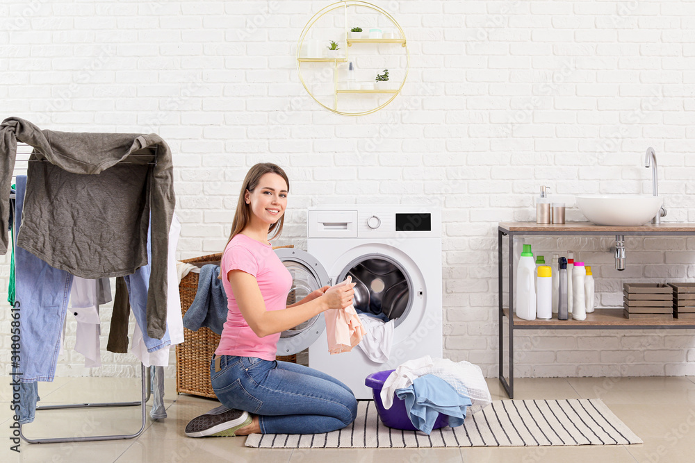 Young housewife washing laundry at home