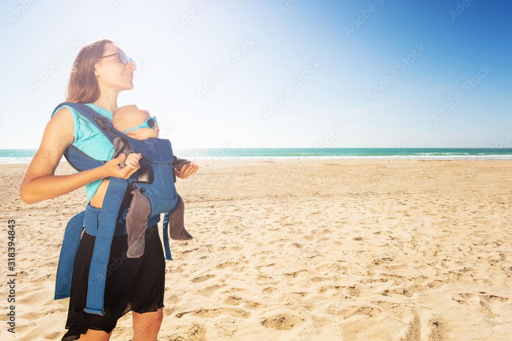 阳光明媚的夏日，海滩上的母亲和婴儿的肖像，背景是大海