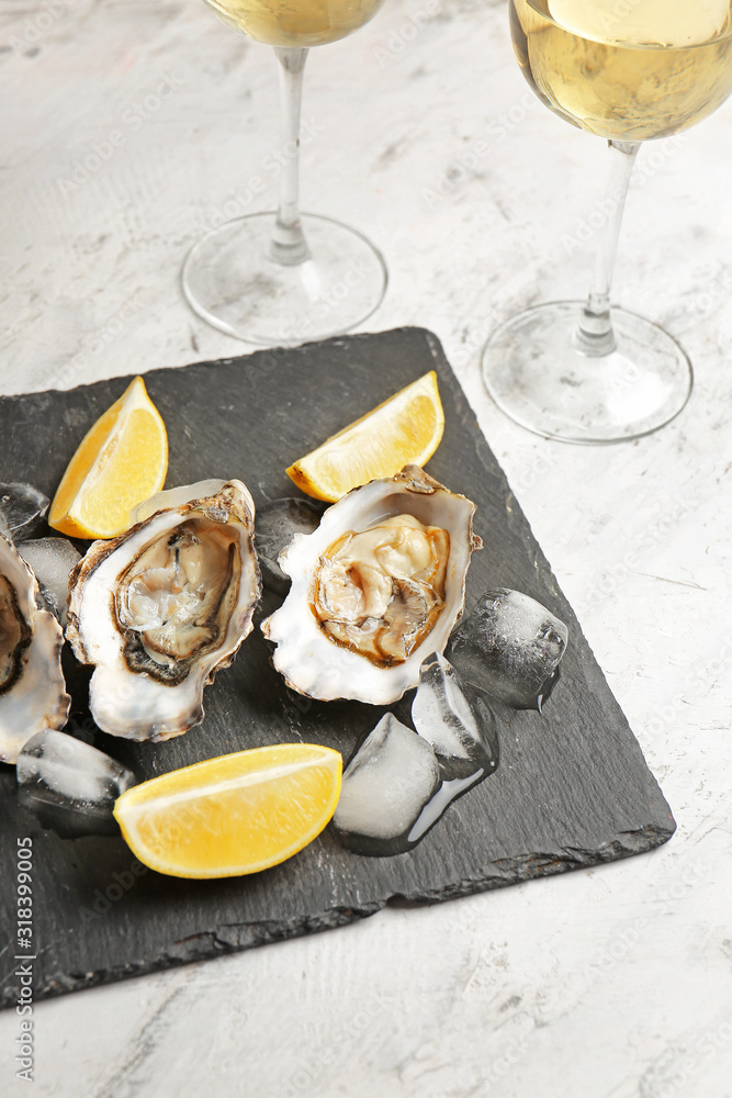 Slate plate with tasty cold oysters and wine on white background