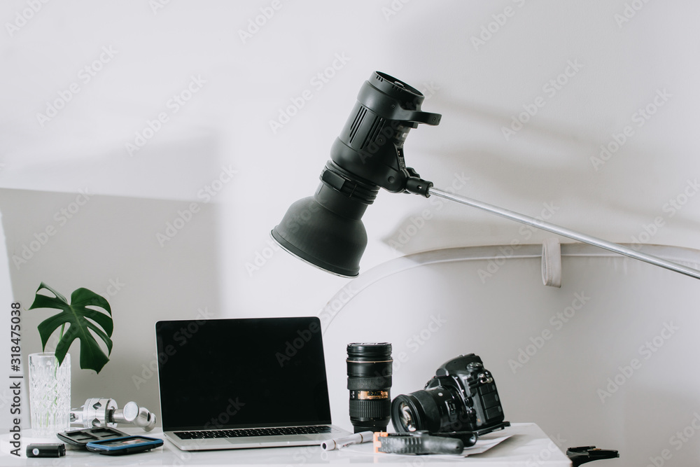 Still life working from home desk with professional photographic equipment, camera, lens, computer m