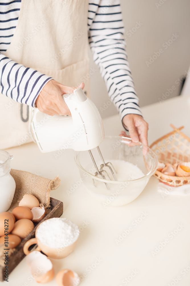 Male hands beating egg whites cream with mixer in the bowl