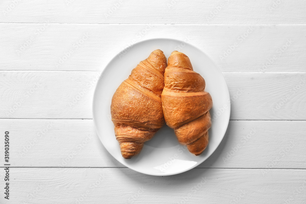 Plate with tasty croissants on table