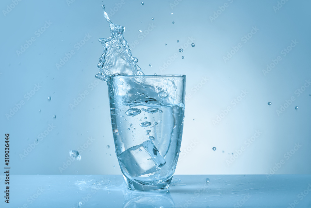 Glass of fresh water with splash on color background