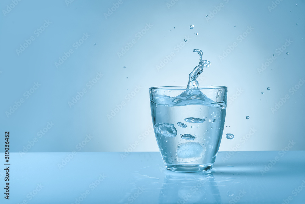 Glass of fresh water with splash on color background