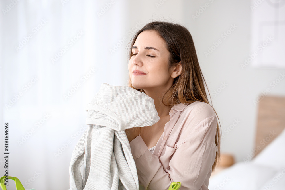 Beautiful young woman with clean laundry at home