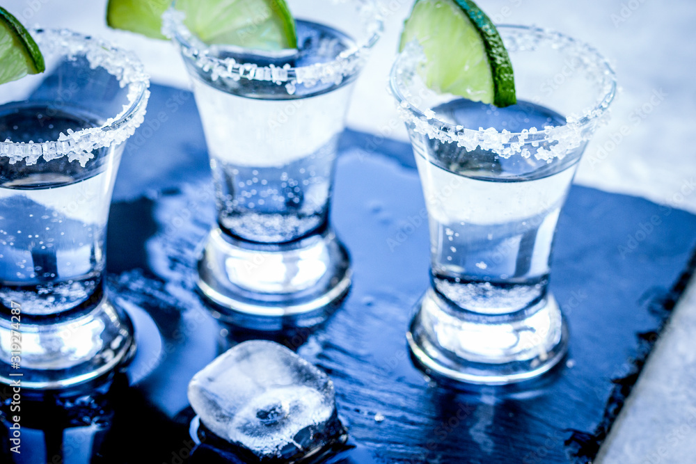 Alcohol shots with ice, lime and salt on gray stone background